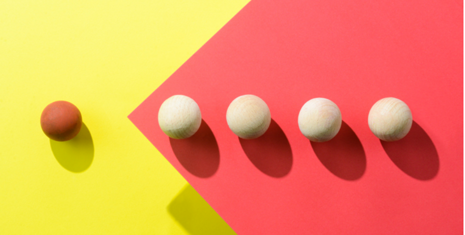 A photo with a yellow and red background with four cream-coloured spheres and one red sphere.