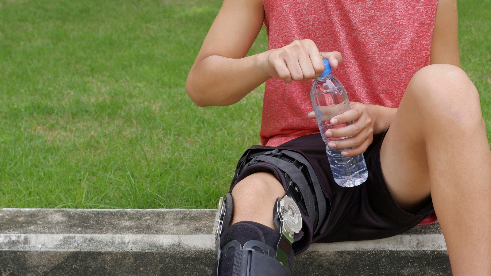 Player with knee brace holding water bottle